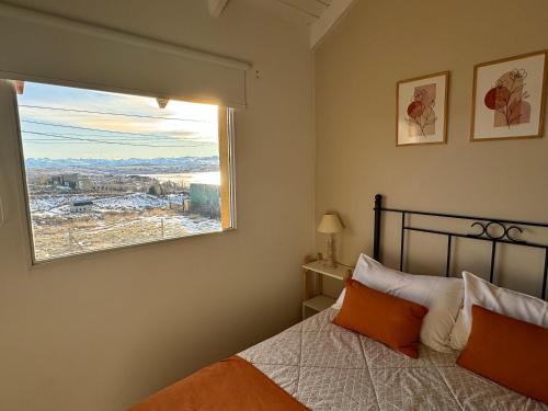 une chambre avec un lit avec des oreillers orange et une fenêtre dans l'établissement TAAR AIKE II (Lugar de Hielo), à El Calafate