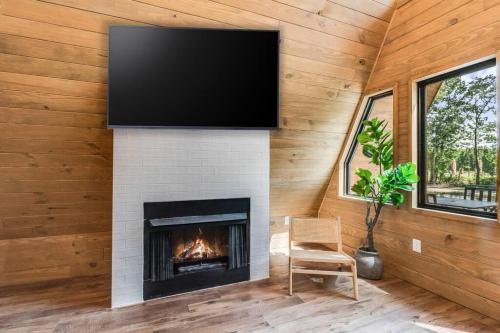 a living room with a fireplace with a flat screen tv at Modern A-Frame Cabin by Rip Van Winkle with Hot Tub in New Iberia