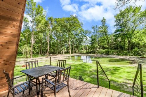 a porch with a table and chairs and a pond at Modern A-Frame Cabin by Rip Van Winkle with Hot Tub in New Iberia