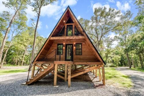 a tiny house on a platform in the woods at Modern A-Frame Cabin by Rip Van Winkle with Hot Tub in New Iberia