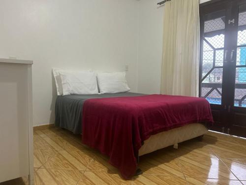 a bedroom with a bed with a red blanket and a window at SOBRADO Com 3 QUARTOS NO CORAÇÃO DO COSTA E SILVA in Joinville