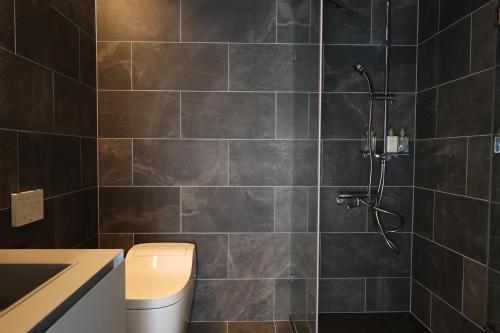 a bathroom with a shower with black tiles at akesuke in Minamiawaji
