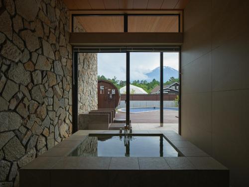 a pool in a house with a stone wall at Private Villa Glampimg 富士山中湖 in Yamanakako