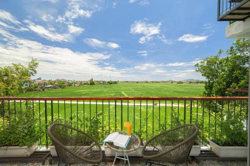 a table and chairs on a balcony with a view of a field at BS Jade Home Hội An in Hoi An