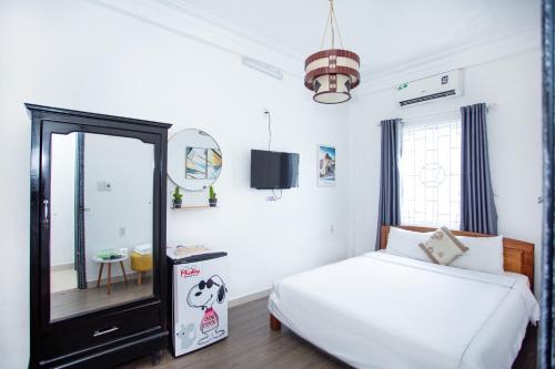 a bedroom with a white bed and a mirror at Mickey Homestay Hue in Hue