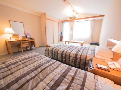 a hotel room with two beds and a desk at Hotel Harvest Skijam Katsuyama in Katsuyama
