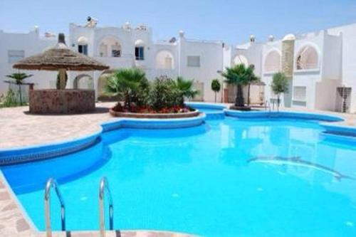 a large pool with blue water in front of a building at Maison Naila in El Jadida