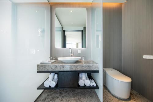 a bathroom with a sink and a mirror and a tub at Awaken Da Nang Hotel in Da Nang