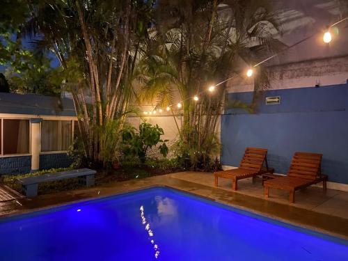 a swimming pool at night with two chairs and lights at Suites del Sureste - Mérida in Mérida