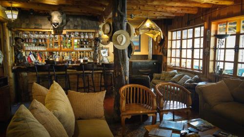 a living room with a bar with a cow head on the wall at Hotel El Barranco in Futaleufú