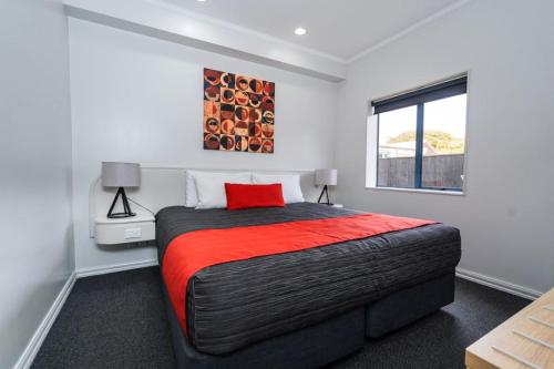 a bedroom with a large bed with a red pillow at Aubyn Court Spa Motel in Palmerston North