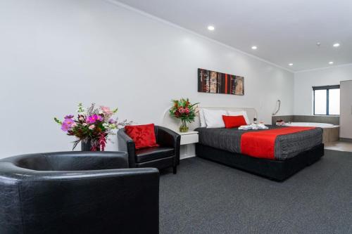 a bedroom with a bed and a chair and a tub at Aubyn Court Spa Motel in Palmerston North