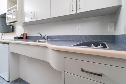 a kitchen with white cabinets and a sink at Aubyn Court Spa Motel in Palmerston North