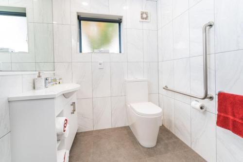 a white bathroom with a toilet and a sink at Aubyn Court Spa Motel in Palmerston North