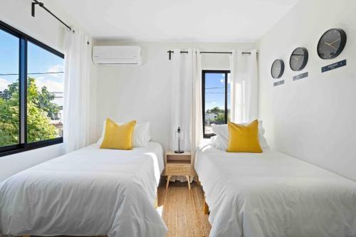 two beds with yellow pillows in a white room at Dorado Tranquil Escape in Dorado