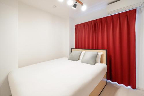 a bedroom with a bed and a red curtain at Rufura Fukusima in Osaka