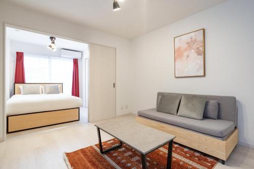 a bedroom with a bed and a couch and a table at Rufura Fukusima in Osaka