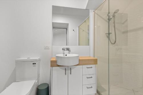 a white bathroom with a sink and a shower at Esplanade 180, Golden Beach in Golden Beach