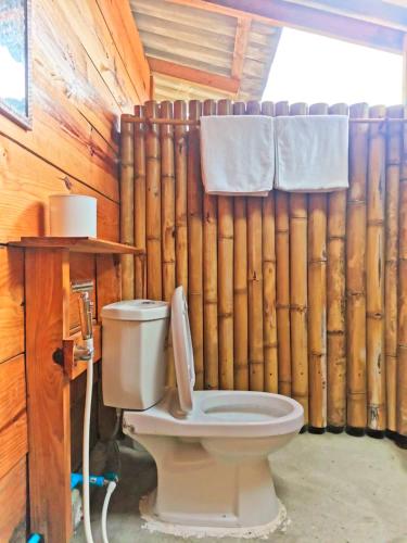 a toilet in a room with a wall of logs at Klang Khao Cabin & Camp in Ban Yang Khun Wang