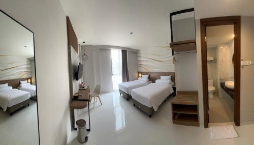 a hotel room with two beds and a mirror at Front One Resort Indraloka Temanggung in Temanggung