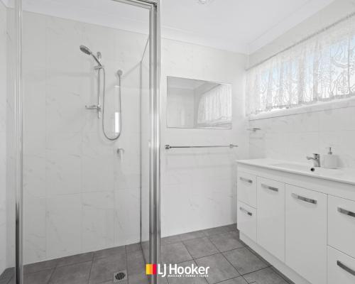 Un baño blanco con ducha y lavabo. en Iluka Lights, en Iluka