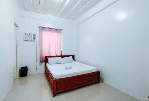 a small bedroom with a bed with a pink window at RedDoorz at Elton Guesthouse in Numancia