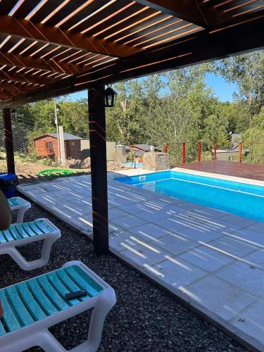 a patio with two chairs and a swimming pool at Cabañas La Arbolada in El Durazno