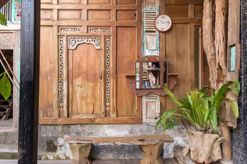 a wooden door with a clock and a bench at TwoSpaces Living at Bunga Desa, Jimbaran in Jimbaran
