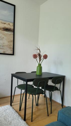 a black dining room table with chairs and a vase with flowers at City Park Appartement in Nitra
