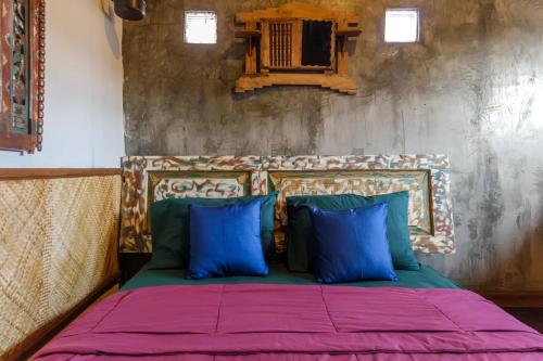 a bed with blue and green pillows in a room at TwoSpaces Living at Bunga Desa, Jimbaran in Jimbaran