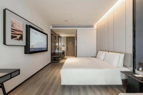 a bedroom with a white bed and a flat screen tv at Atour Hotel Yantai Penglai Government Centre in Penglai