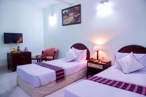 a hotel room with two beds and a tv at Meridian Hotel & Restaurant in Chittagong