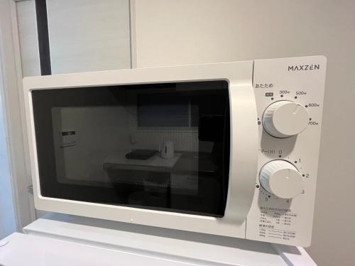 a white microwave oven sitting on a shelf at Cozy inn 西品川101 in Tokyo