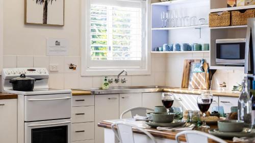 a kitchen with white cabinets and a table with glasses of wine at Beach Bungalow in Corlette