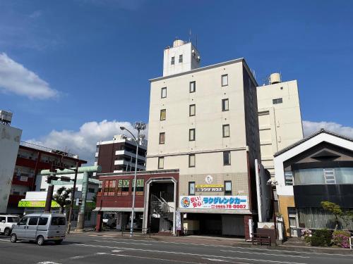 a tall white building on a city street at Rakuda Hotel Jingu in Miyazaki