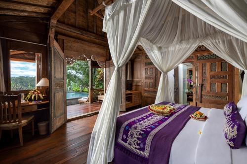 a bedroom with a bed and a desk in a room at Pramana Watu Kurung in Ubud