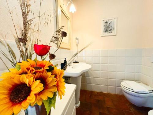 a bathroom with a toilet and a vase of flowers at Nonna Nara Bed & Breakfast in Grosseto