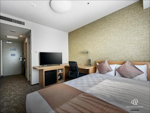 a hotel room with a bed and a desk with a television at Daiwa Roynet Hotel Kyoto-Hachijoguchi in Kyoto