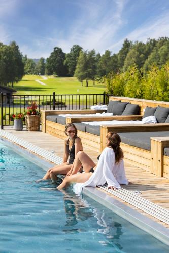 two women sitting on the edge of a swimming pool at Lannalodge in Vintrosa