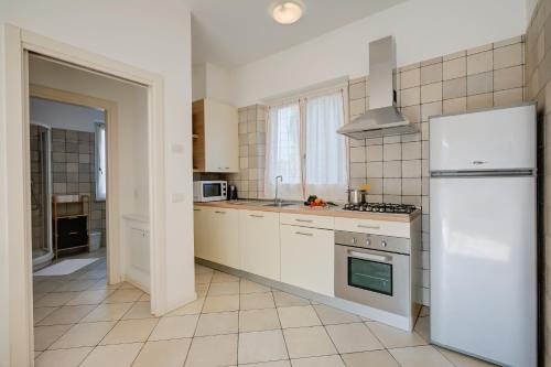 a kitchen with white cabinets and a white refrigerator at Casa al Cor Apartments in Nago-Torbole