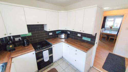 a kitchen with white cabinets and a stove top oven at Cheerful 4-bedroom house in Cheltenham