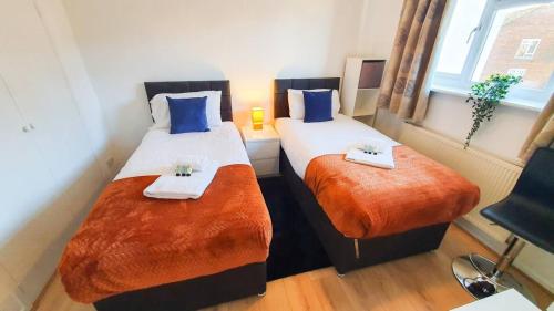 two beds in a room with blue and orange sheets at Cheerful 4-bedroom house in Cheltenham