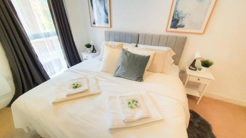 a bedroom with a large white bed with towels on it at Lovely Flat In Kiln Close With Free Parking in Gloucester