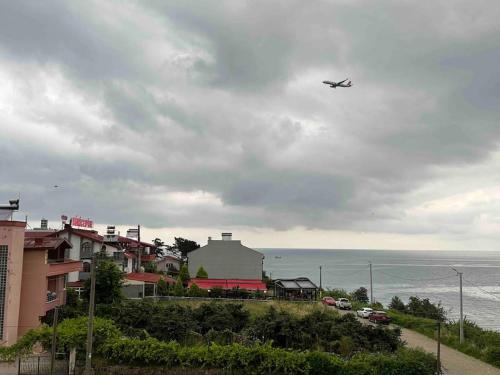 an airplane flying in the sky over the ocean at Plaja yakın konforlu aile yuvası in Piraziz