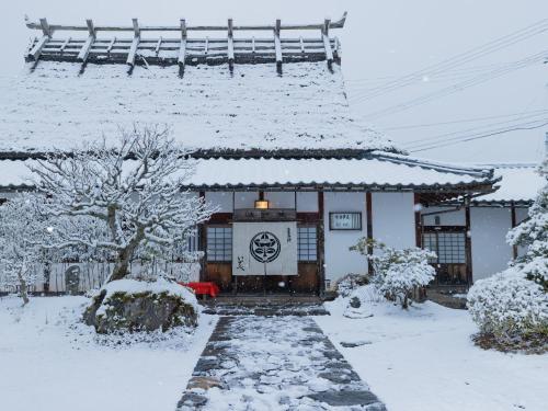 a building with a snow covered roof in a yard at 料理旅館 山里料理 いそべ -Ryokan Isobe- in Kami-hiraya