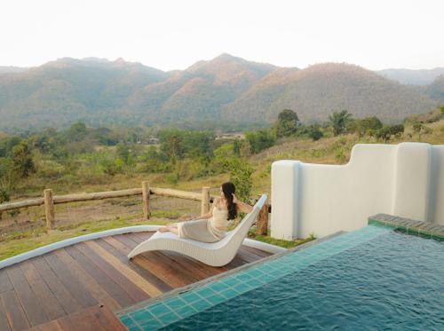 a woman sitting in a hammock next to a pool at Elephantpoolvilla maetang Chiangmai in Ban Muang Kut