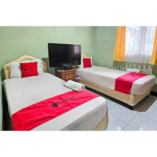 a room with two beds and a tv in it at RedDoorz at Linggarjati Kuningan in Kuningan