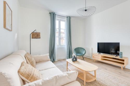 un salon blanc avec un canapé blanc et une télévision dans l'établissement Appartement Ylang - La Maison Heureuse - Welkeys, à Saint-Georges-dʼOléron