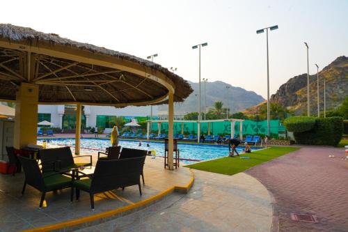 a swimming pool with chairs and a table and a umbrella at Boutique Hotel in Fujairah