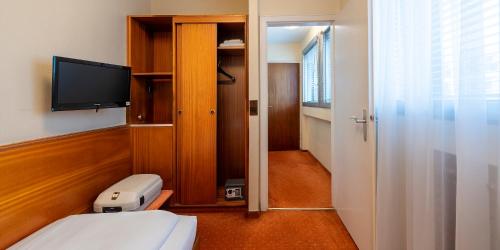 a small room with a bed and a television at PLAZA INN Rieker Stuttgart Hauptbahnhof in Stuttgart